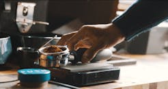 咖啡师的手特写，在现代厨房中精确准备咖啡渣