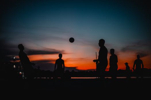 Silhouetted group playing soccer on the Amazon Riverbank at sunset in Manaus, Brazil.