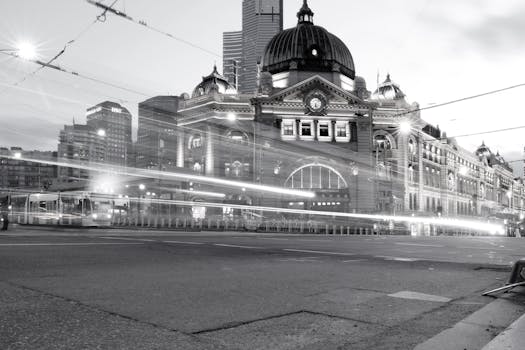 Dynamic night view of Flinders Street Station in Melbourne with light trails from passing trams.