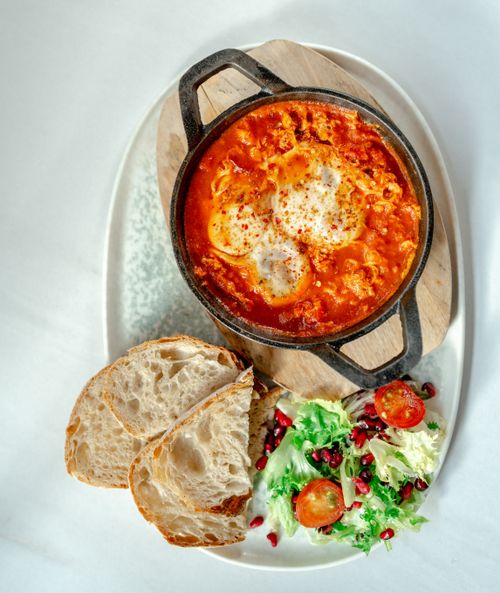 Free Top view of shakshuka served with bread and salad. Perfect for brunch ideas. Stock Photo