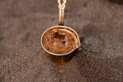 Authentic Turkish coffee brewing in sand, showcasing rich textures and cultural tradition.
