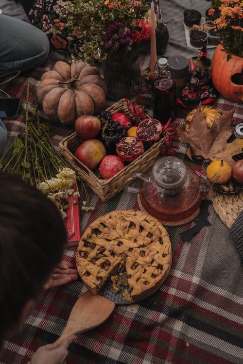 Free Cozy autumn picnic setup with pie, pumpkins, pomegranates, and fall decor. Stock Photo