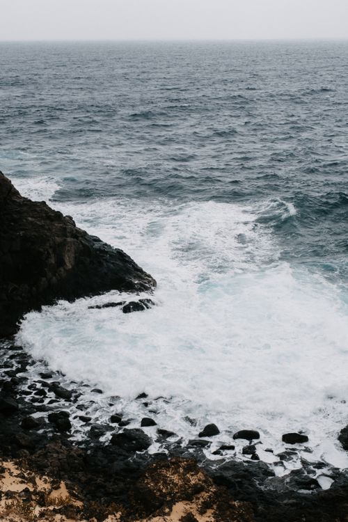 Free Powerful ocean waves crashing onto a rocky volcanic coastline, a natural and intense seascape. Stock Photo