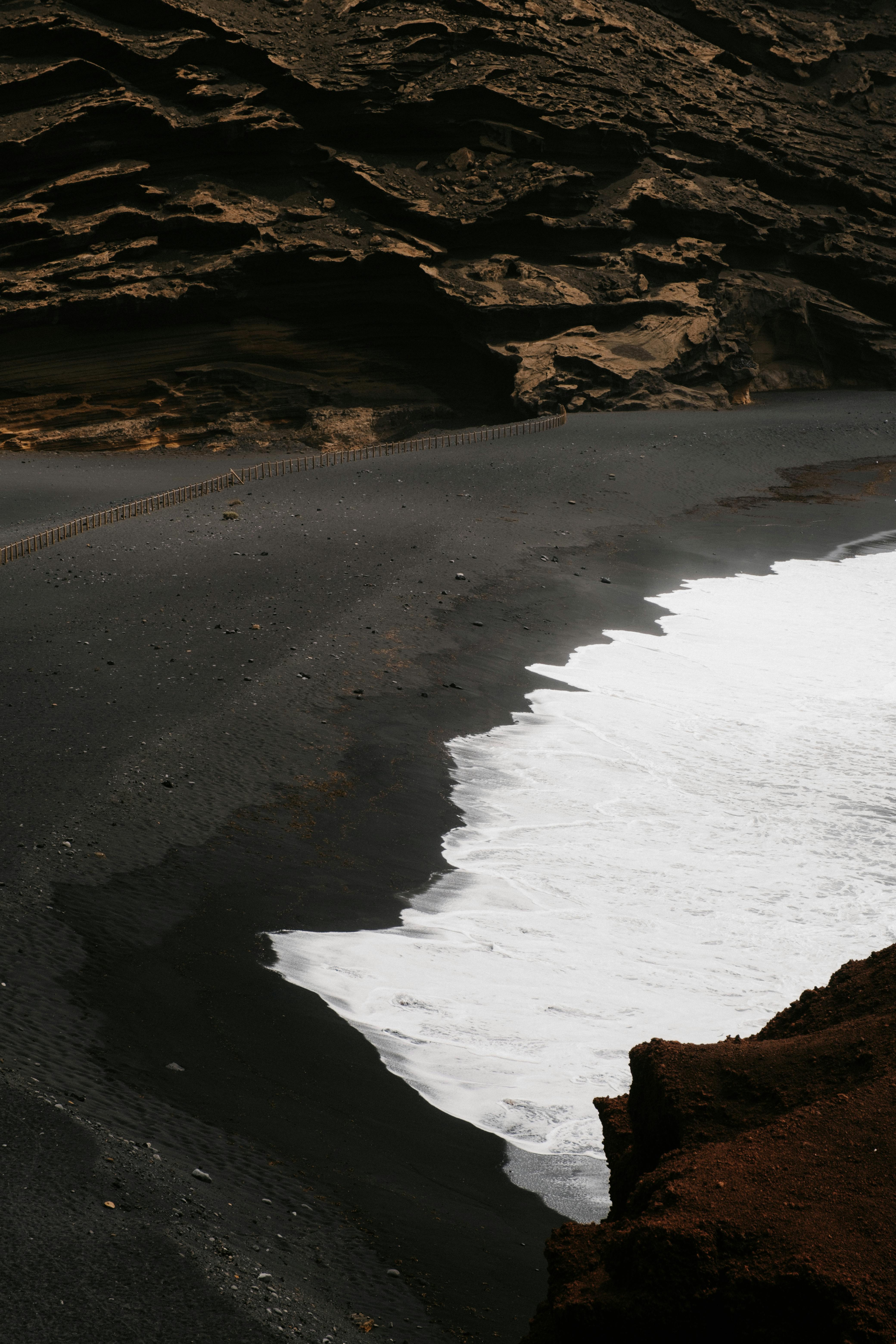 A striking view of El Golfo beach with its unique black sand and rugged cliffs.