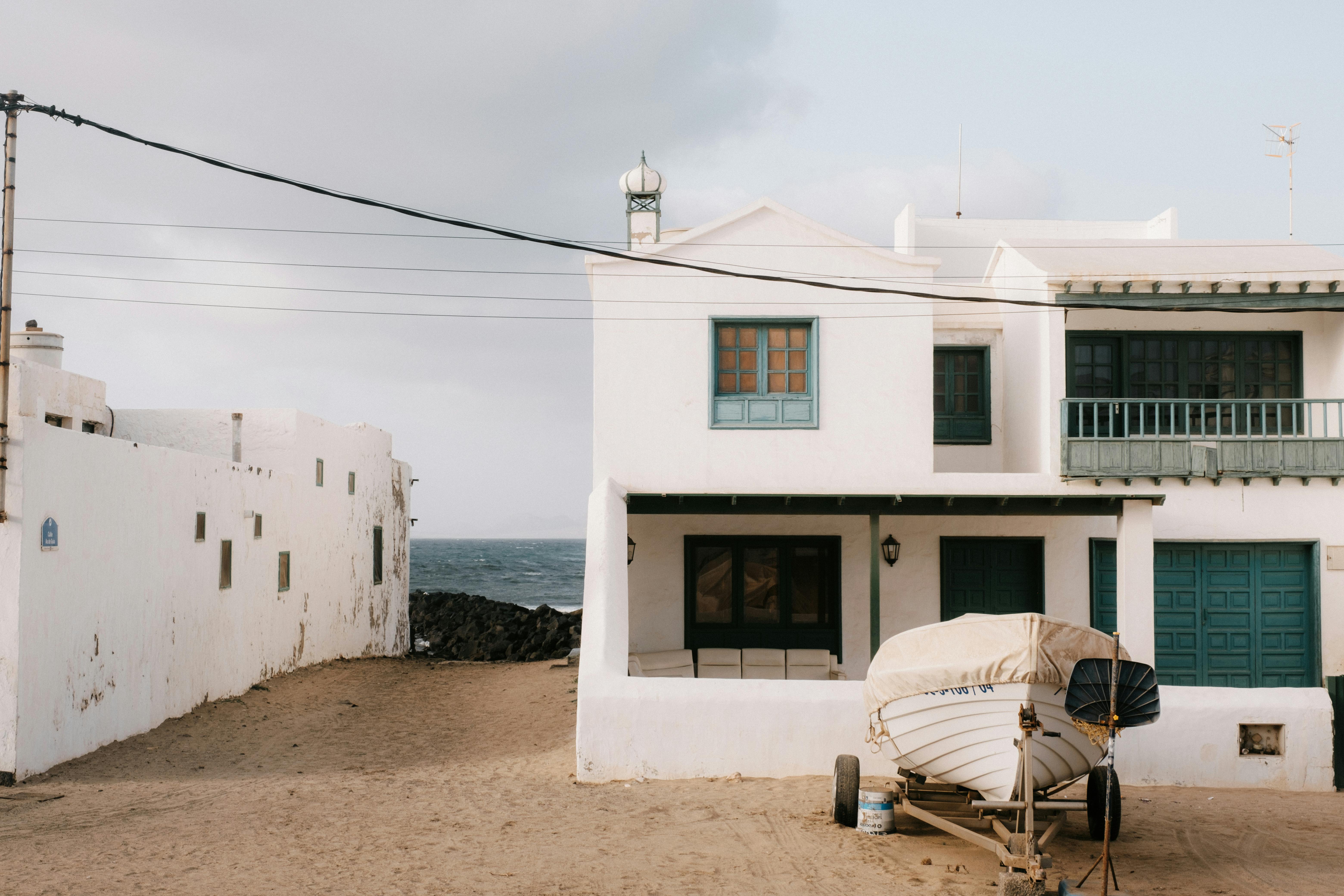 White coastal house and boat create a tranquil scene in Lanzarote, Spain.