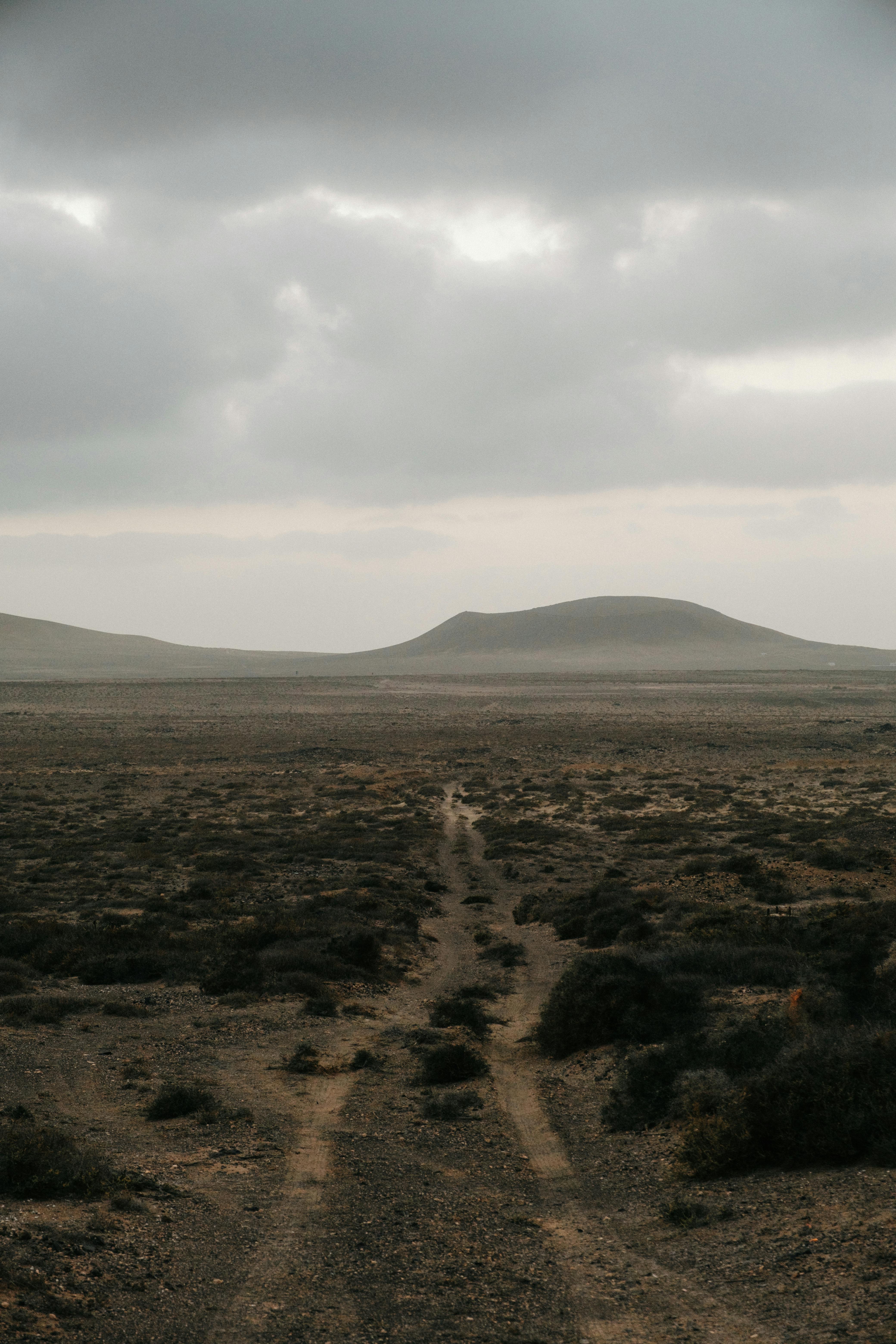 Moody desert scene with a dirt road and cloudy sky, showcasing Lanzarote's unique terrain.