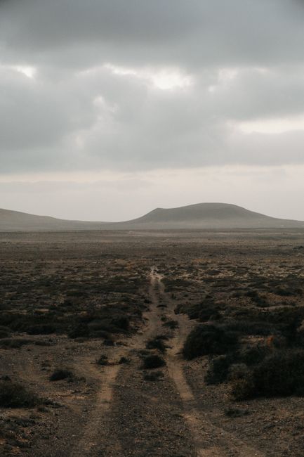 Moody desert scene with a dirt road and cloudy sky, showcasing Lanzarote's unique terrain.