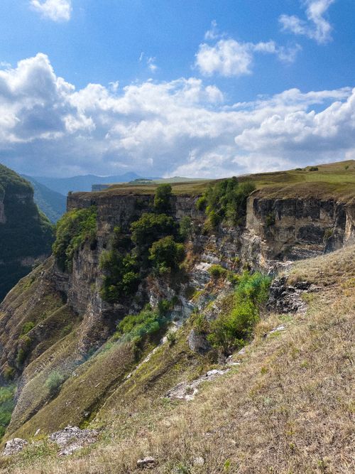 Free Stunning cliff landscape with lush greenery and blue sky, ideal for nature enthusiasts. Stock Photo