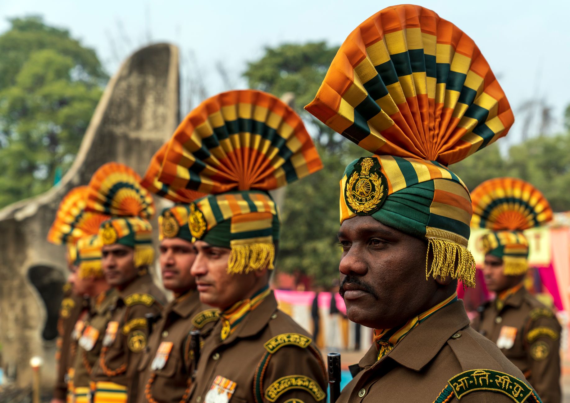Indian soldiers in ceremonial uniforms with ornate headdresses standing outdoors.