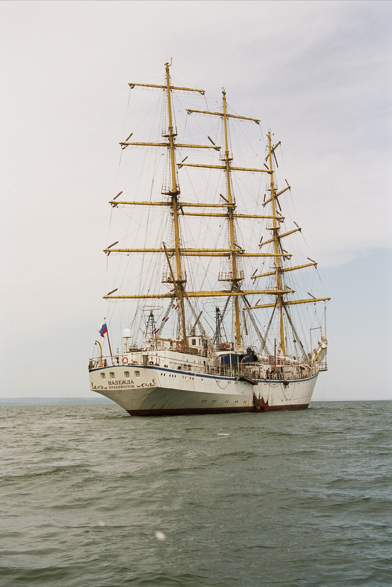 Grand tall ship with white sails sailing on the open ocean under a clear sky, its tall masts fully set