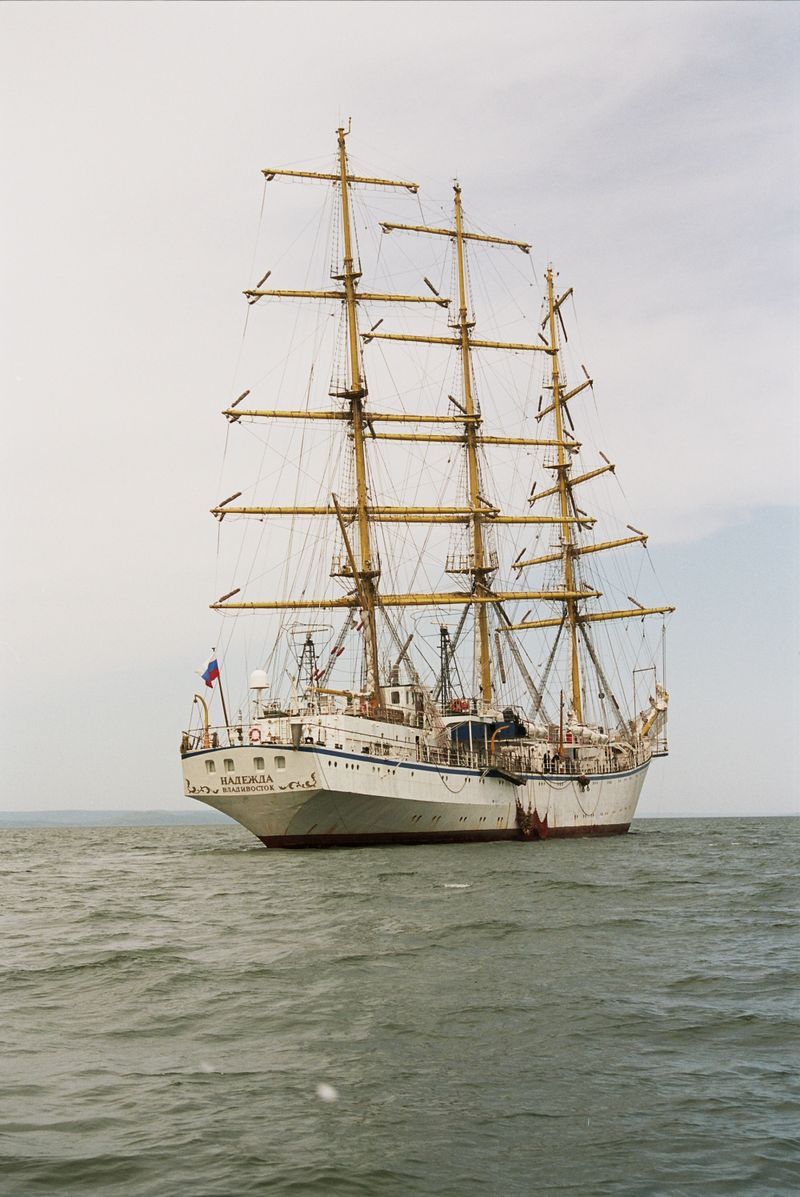 Three-masted white sailing ship with all sails raised crossing the open sea at speed