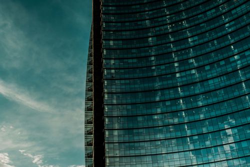 Free Curved glass façade of a modern skyscraper with a dramatic sky in the background. Stock Photo