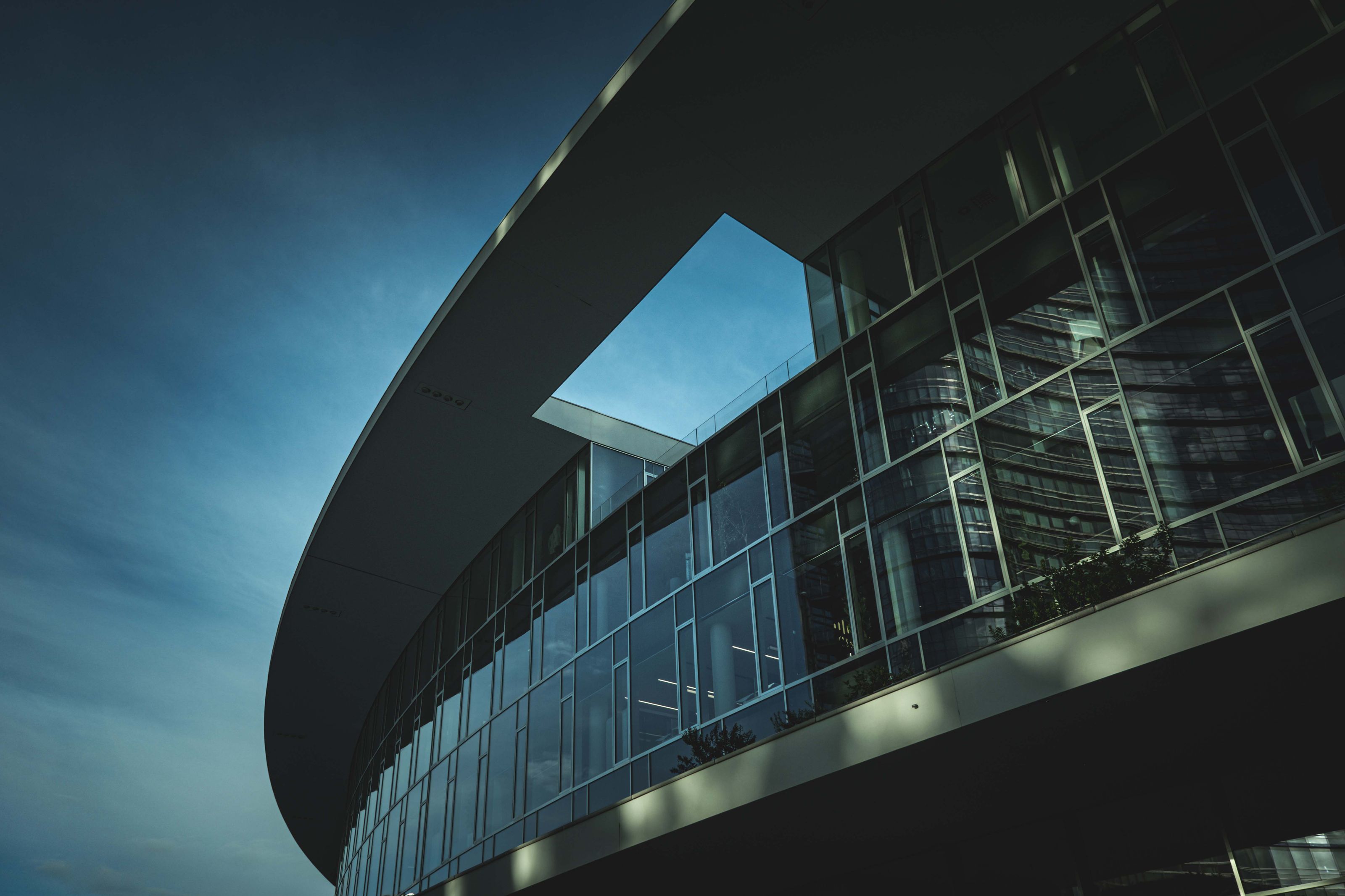 An architectural shot of a modern curved glass building with a dramatic sky.