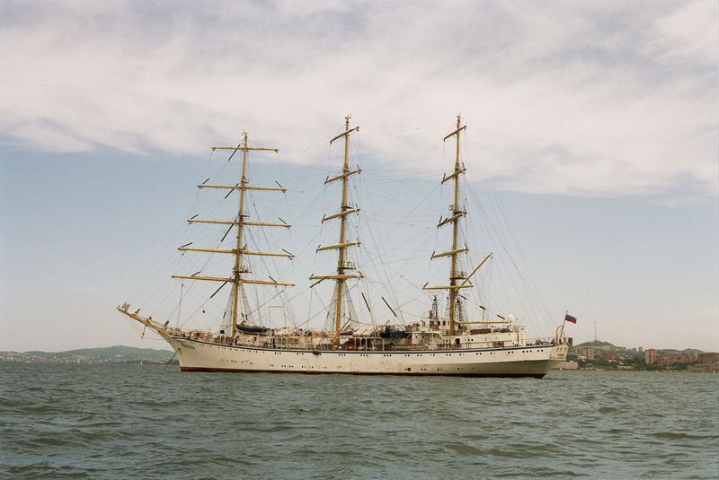 White clipper ship sailing on the open ocean under a dramatic cloudy sky