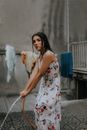Woman in Long Floral Dress Holding Hose Pipe