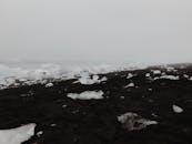 冰岛黑沙滩的风景，在雾蒙蒙的冬季背景下散落着冰块