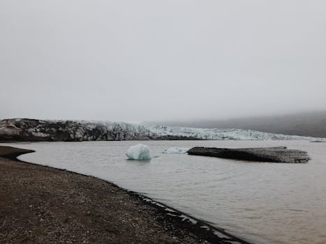 冰岛崎岖的地形中，冰川与大海交汇，景色宁静而阴沉
