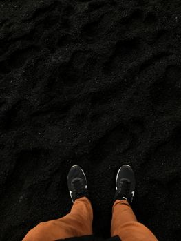 A person stands on a black sand beach in Iceland, wearing brown pants and sneakers.. pexels, person, stands