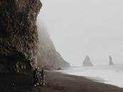 冰岛黑色沙滩上，朦胧的景色、高耸的悬崖和海塔映入眼帘