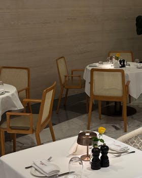 Elegant restaurant setting in Dubai with stylish wooden chairs and white tablecloths.
