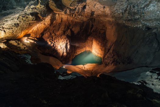 Discover the breathtaking beauty of an illuminated underground cave with a serene water pool in Новый Афон.