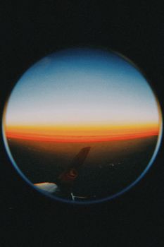 Stunning fisheye lens view from airplane showcasing vibrant sunset over Romania's horizon.