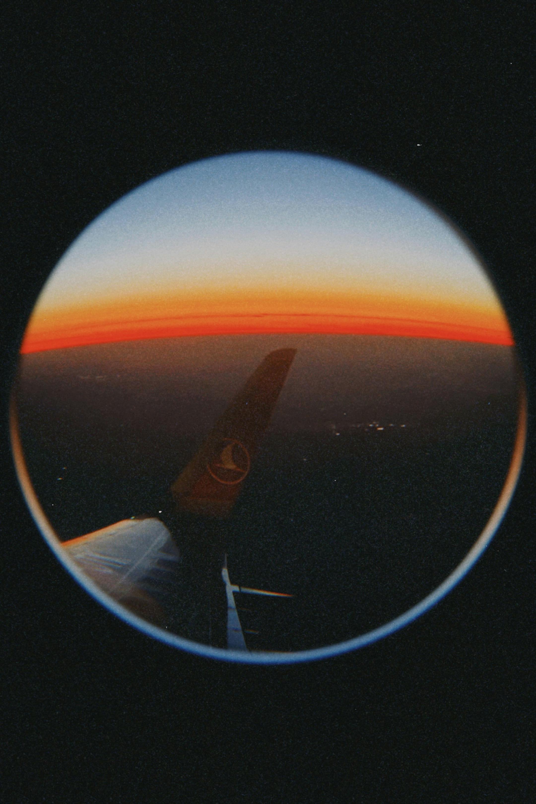Stunning fisheye lens airplane wing view with vibrant sunset hues.