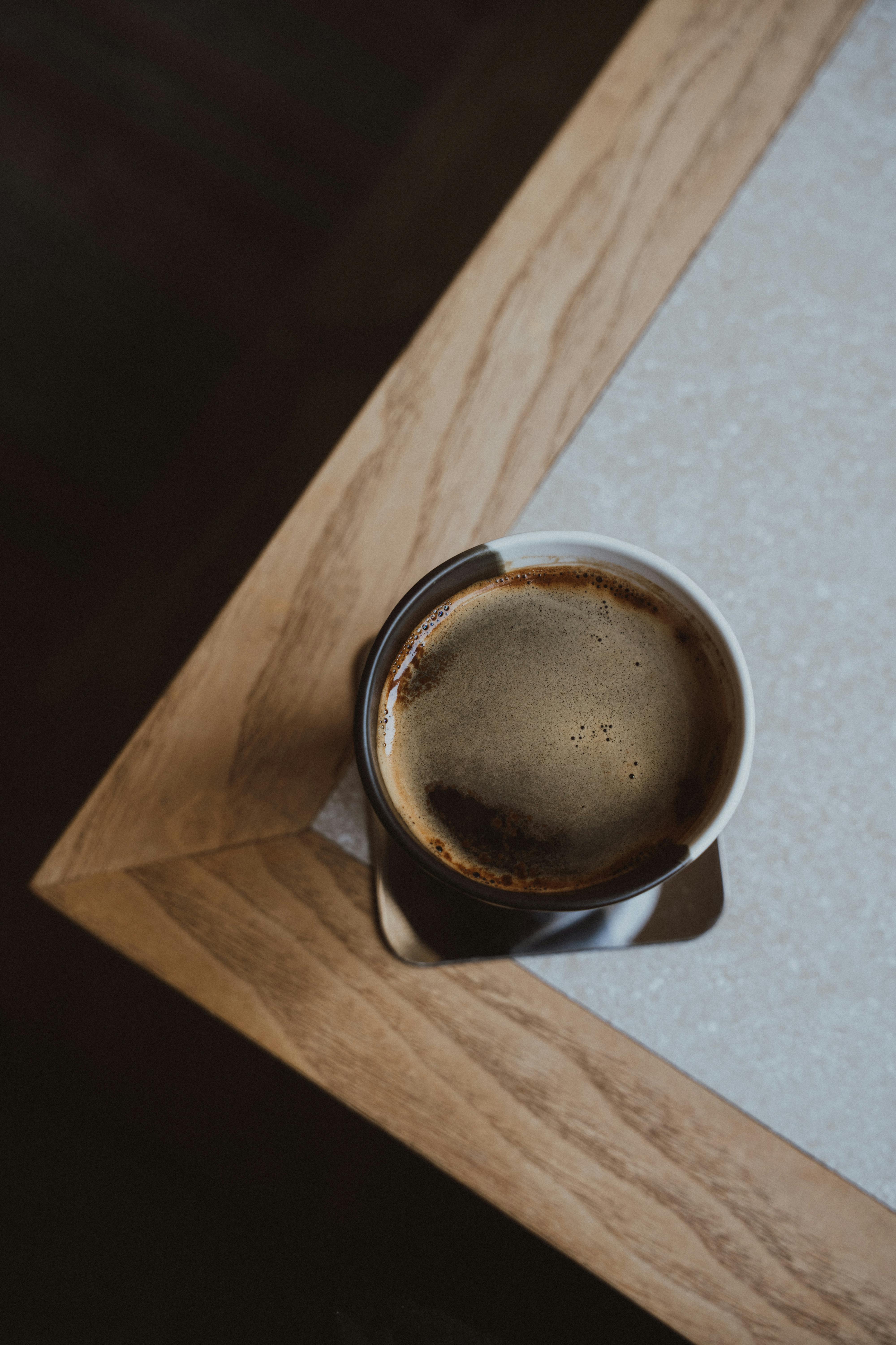Free An overhead view of a coffee cup on a wooden tabletop, embodying morning calm and simplicity. Stock Photo