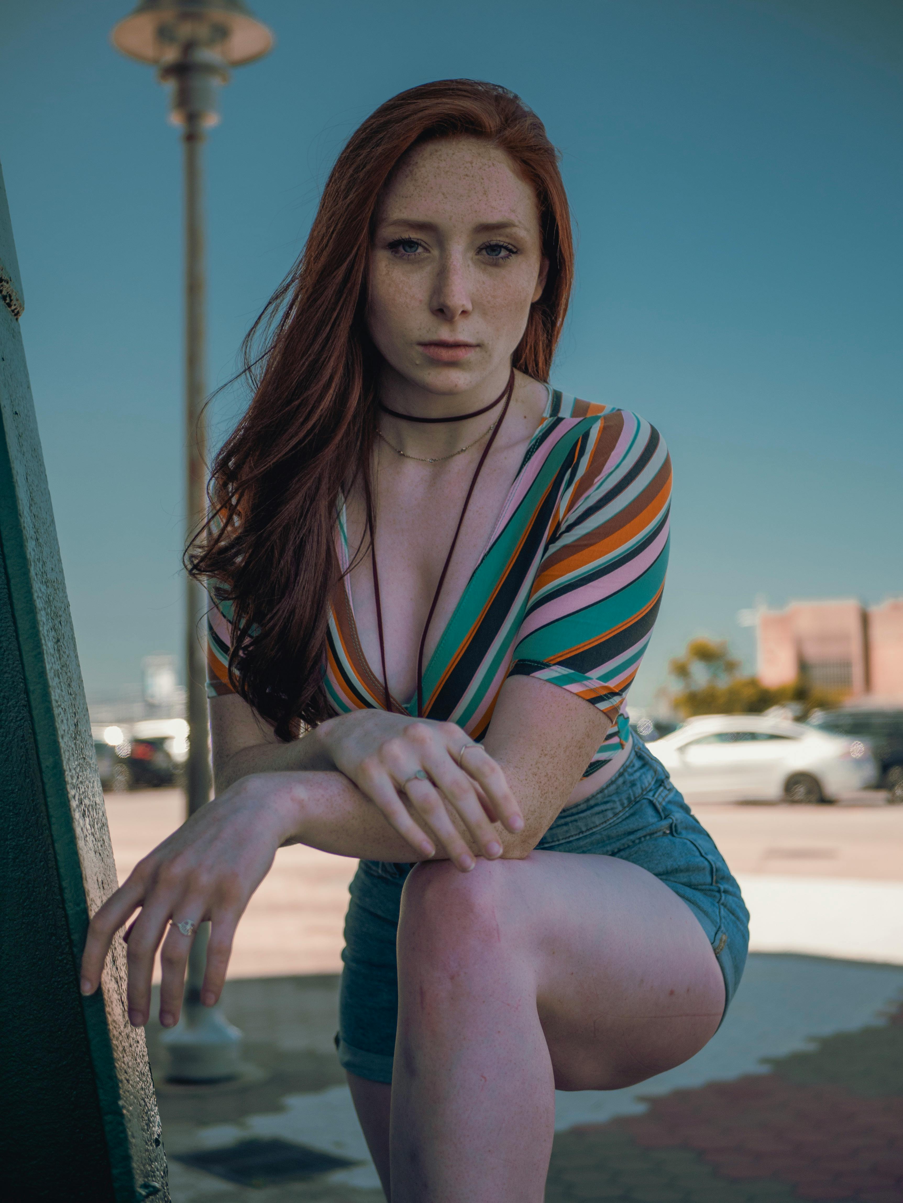 woman wearing multicolored striped deep v neck top and blue denim shorts