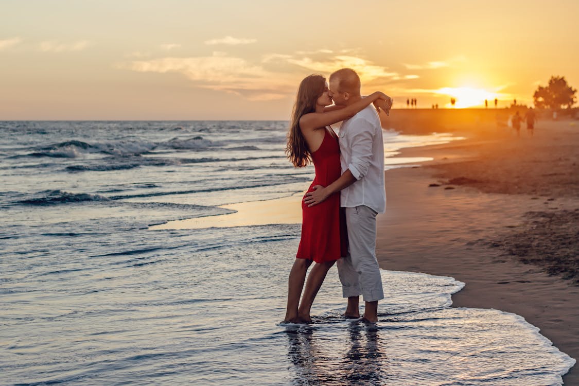 無料 ゴールデンアワーの間にビーチでキスするカップル 写真素材