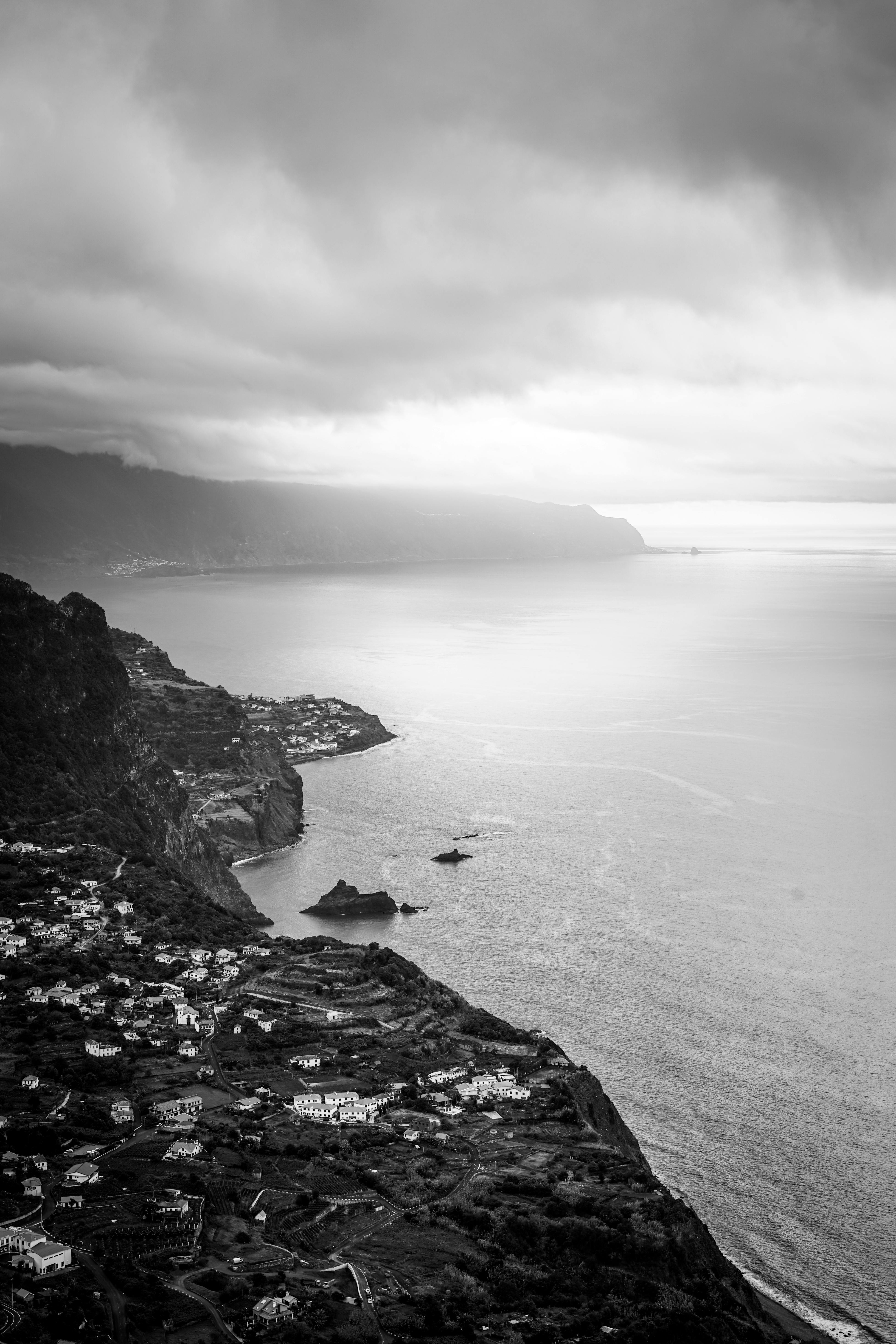 Aerial view of a dramatic coastal landscape with cliffs and ocean in black and white.