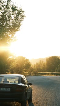 Serene road scene with car and sunrise lighting the path.