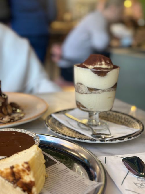 Free A delectable tiramisu dessert along with cakes in a cozy cafe setting. Stock Photo
