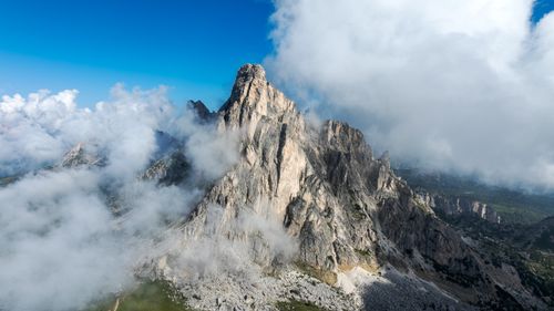 Free Majestic mountain peak in the Alps surrounded by clouds and blue sky. Stock Photo