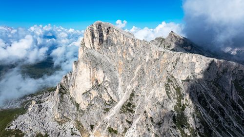 Free Stunning aerial shot of rugged alpine mountains with blue skies and white clouds. Stock Photo