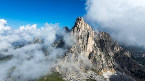 Free Breathtaking view of the Dolomite mountains with clouds enveloping the peaks under a blue sky. Stock Photo