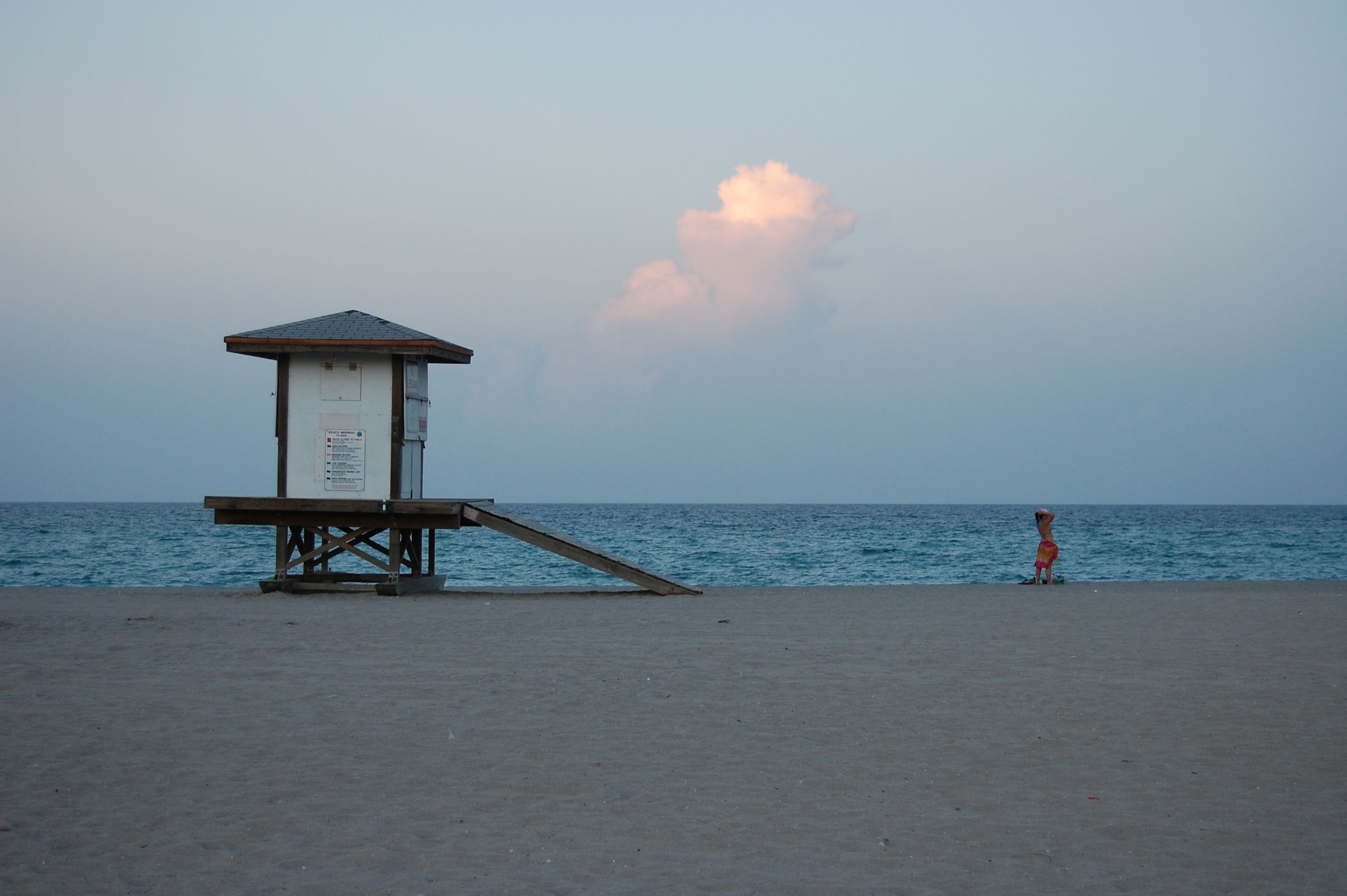 A serene Miami Beach scene featuring a lifeguard tower and a lone person at sunset.