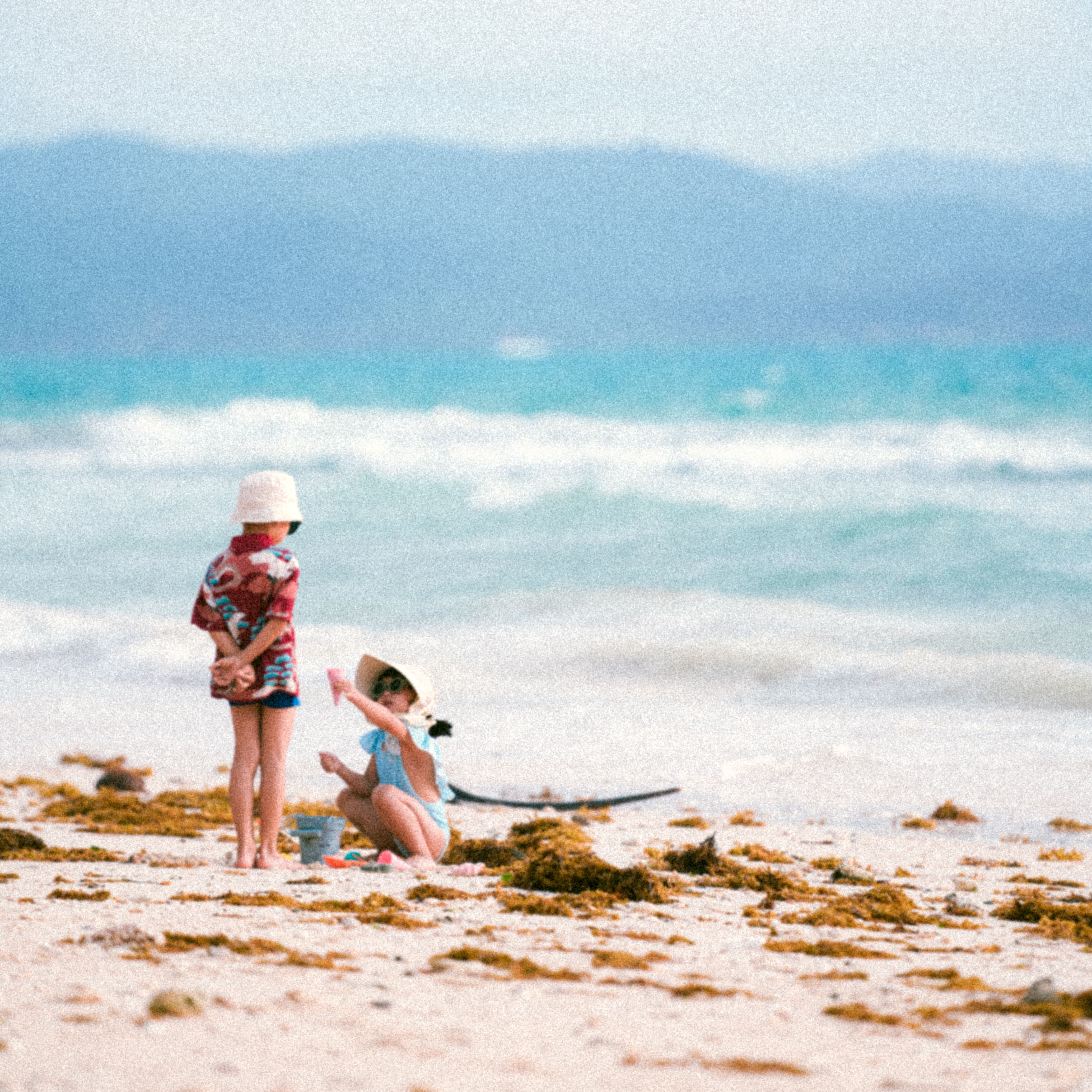 Two children enjoy playing in the sand on a beautiful beach day.