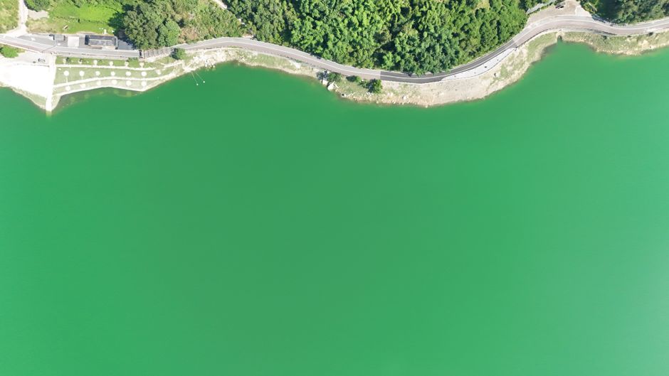 Unbeatable Zhangjiajie Private Helicopter Tour to Explore Real Avatar World Review 2026 - Aerial view depicting a vibrant green lake bordered by a winding road and lush greenery.