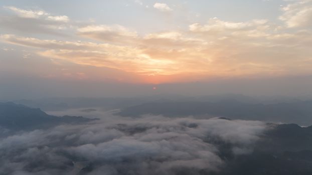 Breathtaking aerial view of mist-covered mountains with a vibrant sunrise sky.