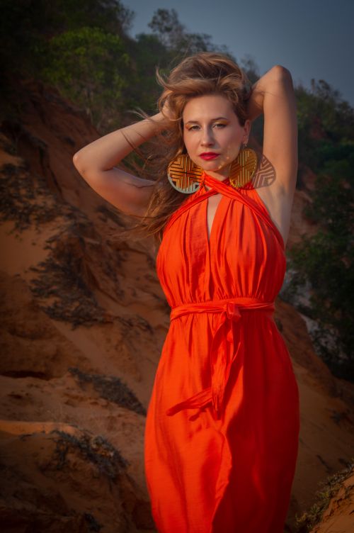 Free Elegant woman in a red dress posing against a natural rocky background. Stock Photo