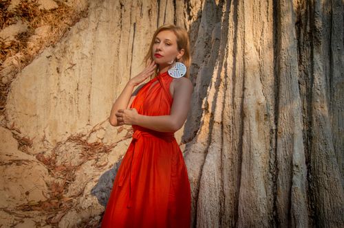 Free A stylish woman in a red dress poses confidently against a textured tree background. Stock Photo