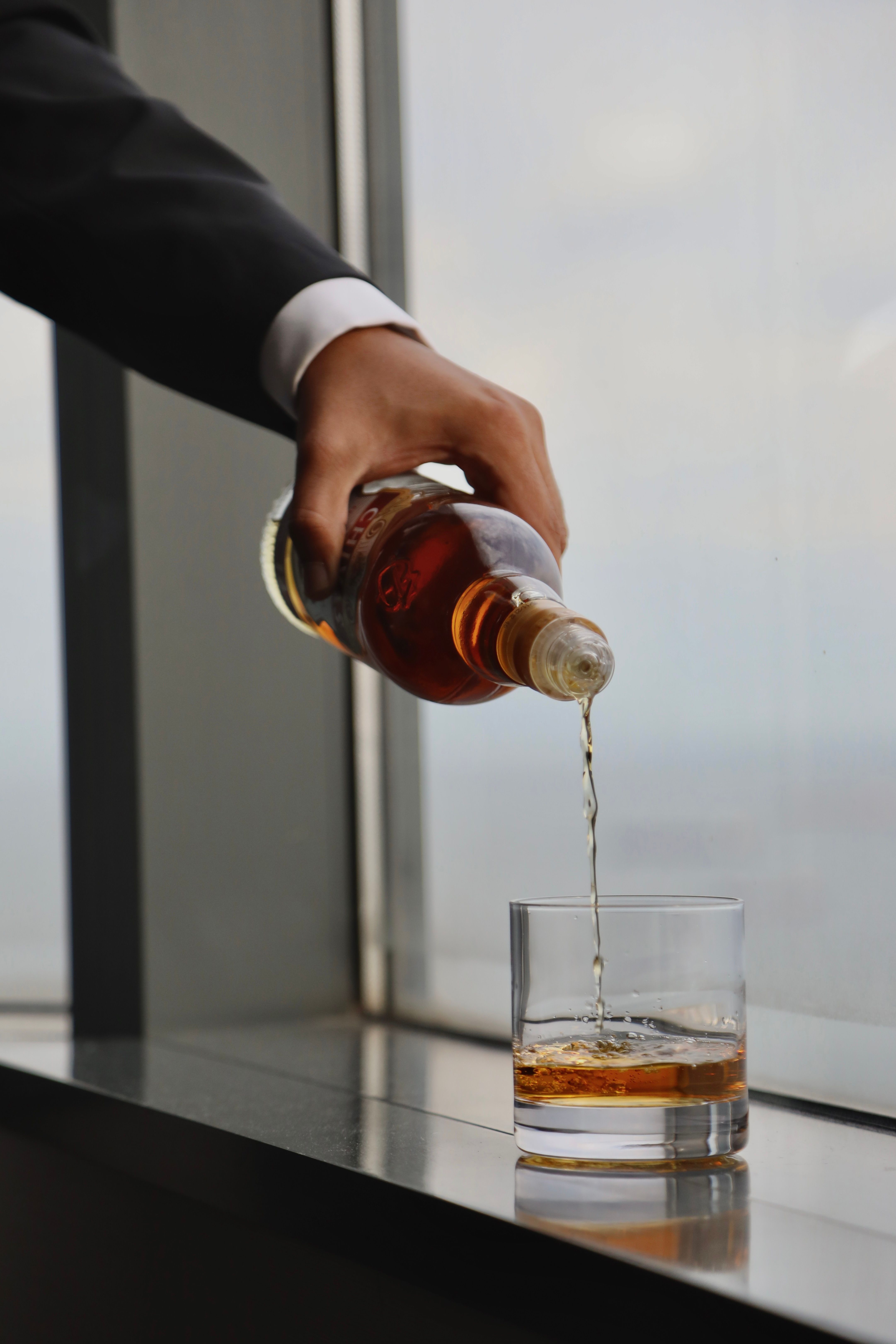 Close-up view of whiskey being poured into a glass by a window in Istanbul.