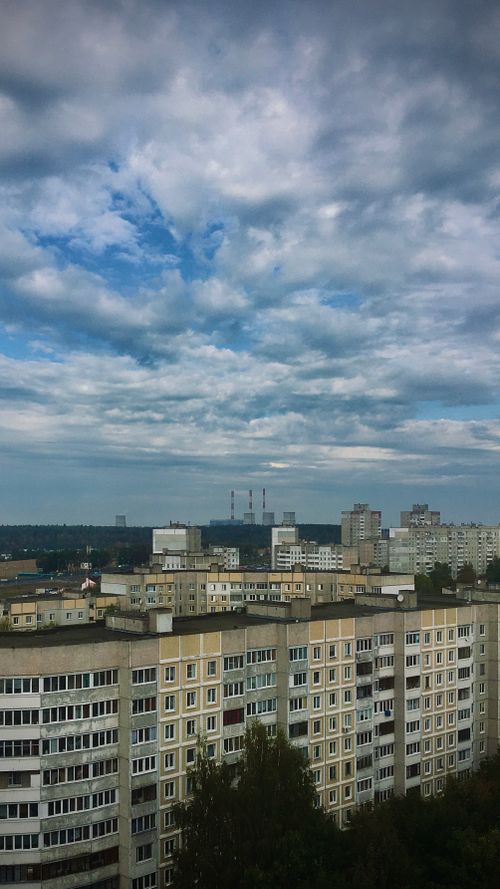 Free View of Minsk cityscape with overcast sky, featuring residential buildings and a power plant. Stock Photo