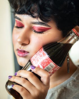 Close-up portrait of a woman with bold makeup holding a soda bottle, conveying a retro fashion vibe.