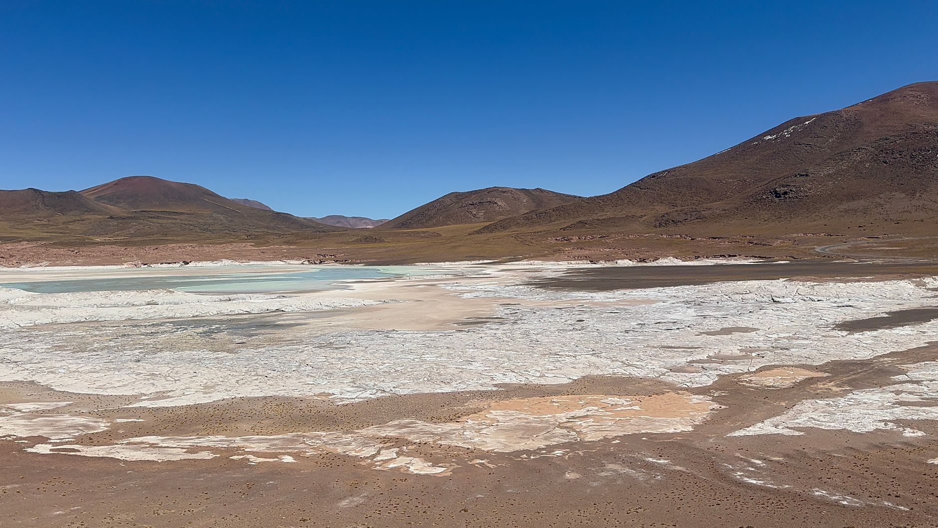 Beautiful salt flats with mountains under clear blue skies in the Andes.