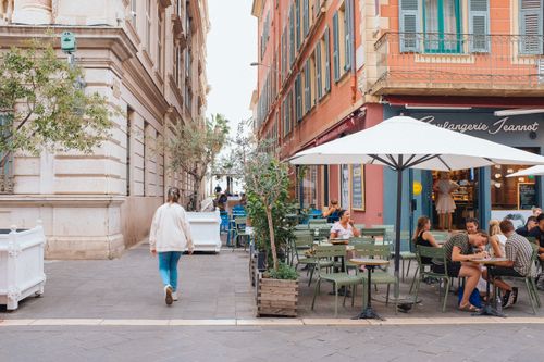Free A quaint European street cafe with people enjoying outdoor seating on a sunny day. Stock Photo