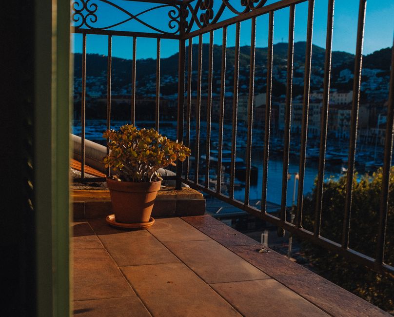 Mediterranean balcony at sunset with terracotta tiled floor, wrought iron railing and harbor view