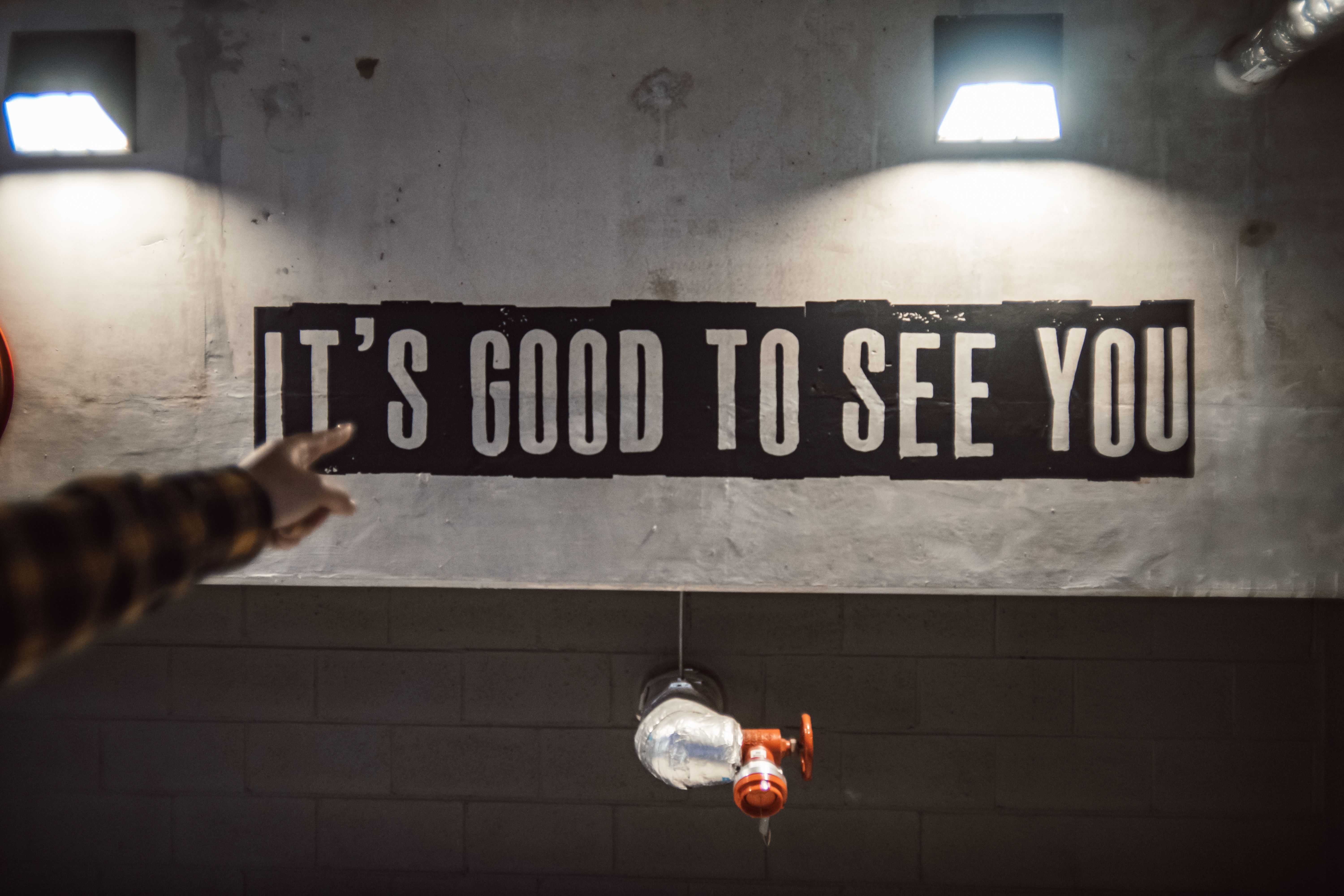 A hand points at bold typography on an urban wall with lights.