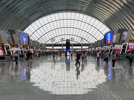A bustling modern airport terminal with geometric ceiling design and reflective floors.